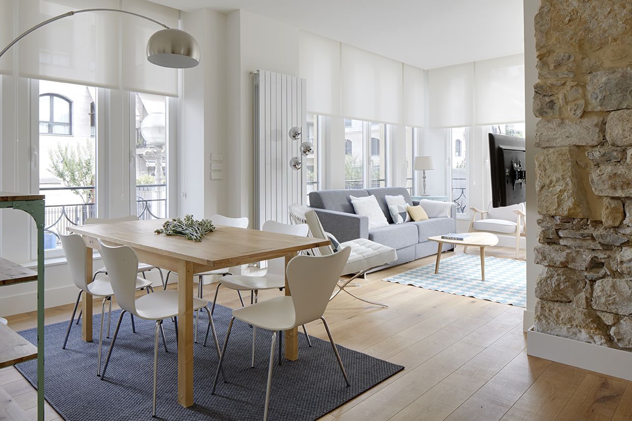 Salón-comedor del apartamento Beduria A con pared de piedra original, mesa de madera y grandes ventanales