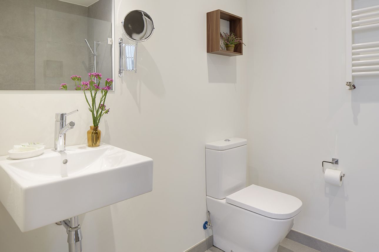 Baño adaptado con lavabo accesible, espejo grande y radiador toallero